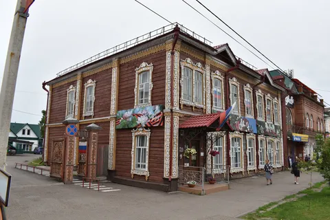 Двухэтажное деревянное здание начала XX века с двумя фронтонами, украшенными обильной пропильной резьбой по карнизу, с наличниками, с решетками художественного литья в цокольном этаже, ныне художественная школа